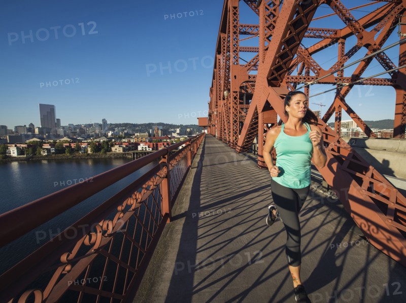 Caucasian woman jogging on urban bridge