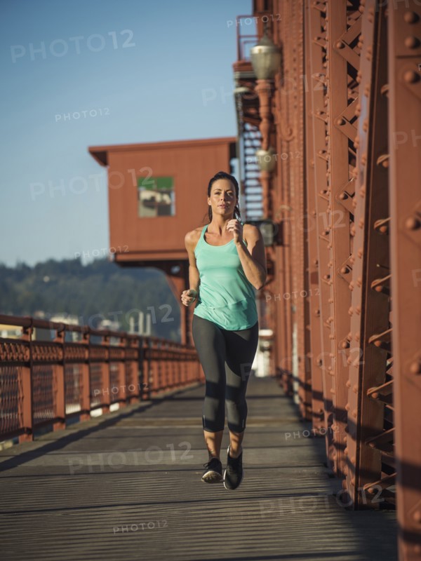 Caucasian woman jogging on urban bridge