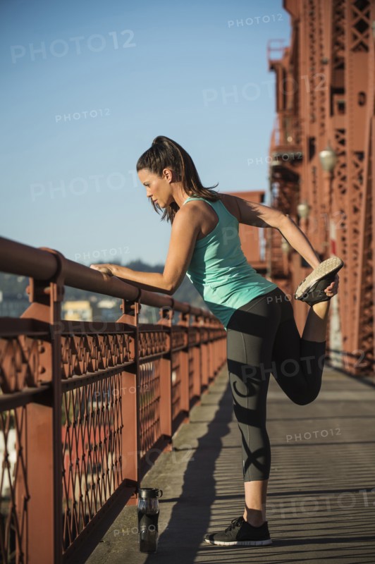 Caucasian woman stretching on urban bridge