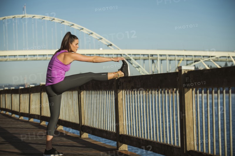 Caucasian woman stretching on urban bridge