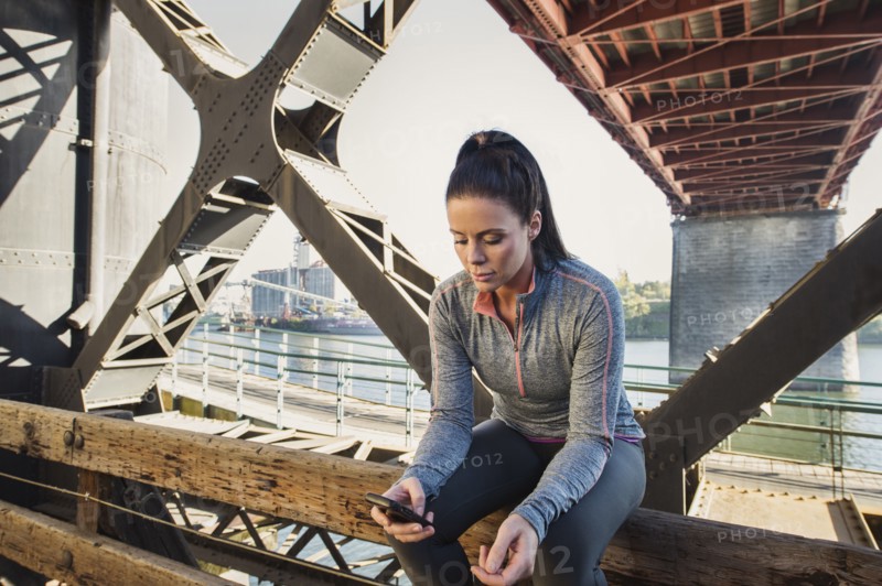 Caucasian woman sitting on urban bridge