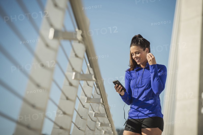 Caucasian woman using cell phone on urban bridge