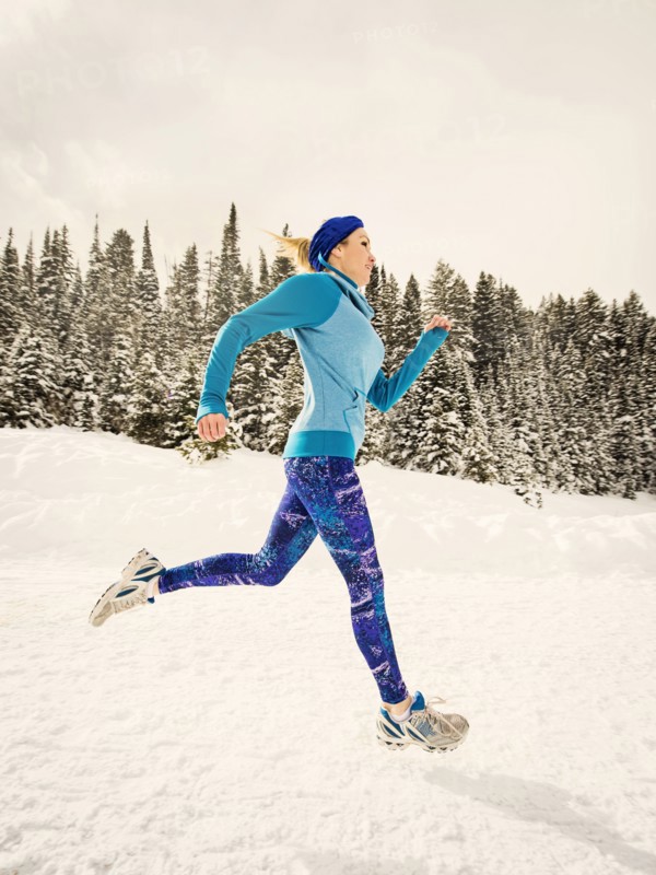 Caucasian woman running in snowy landscape