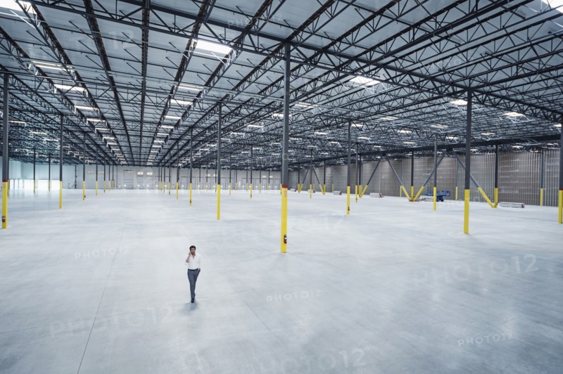 Indian businessman talking on cell phone in empty warehouse