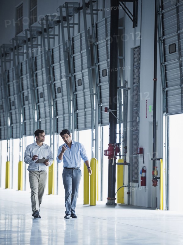 Businessmen walking with clipboard near open loading dock doors