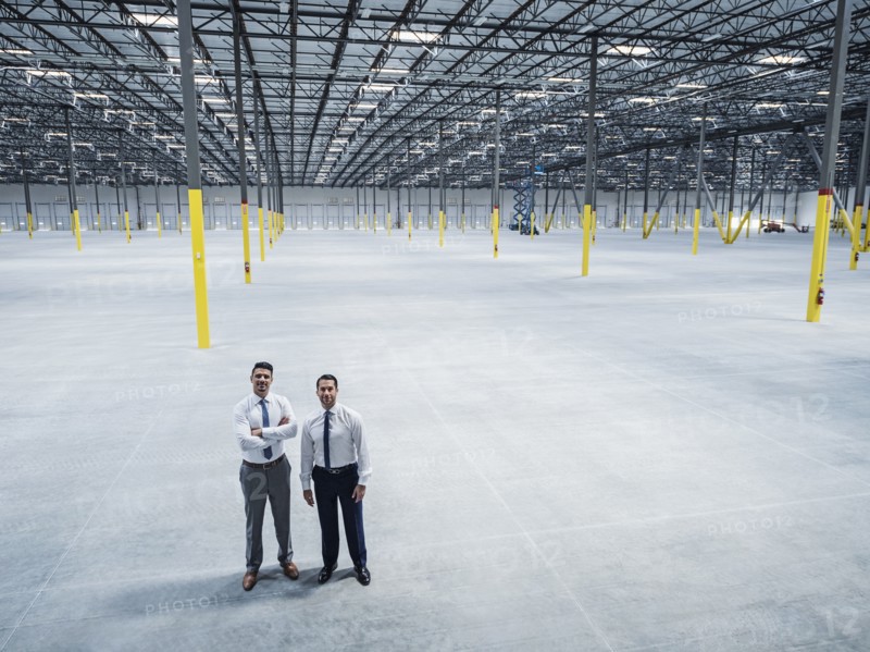 Smiling businessmen posing in empty warehouse