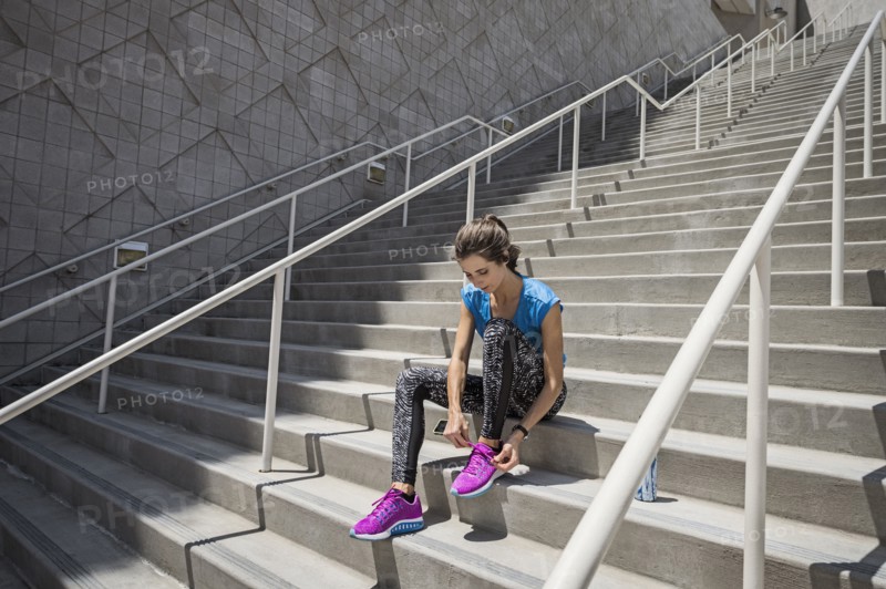 Caucasian woman sitting on staircase tying shoelace