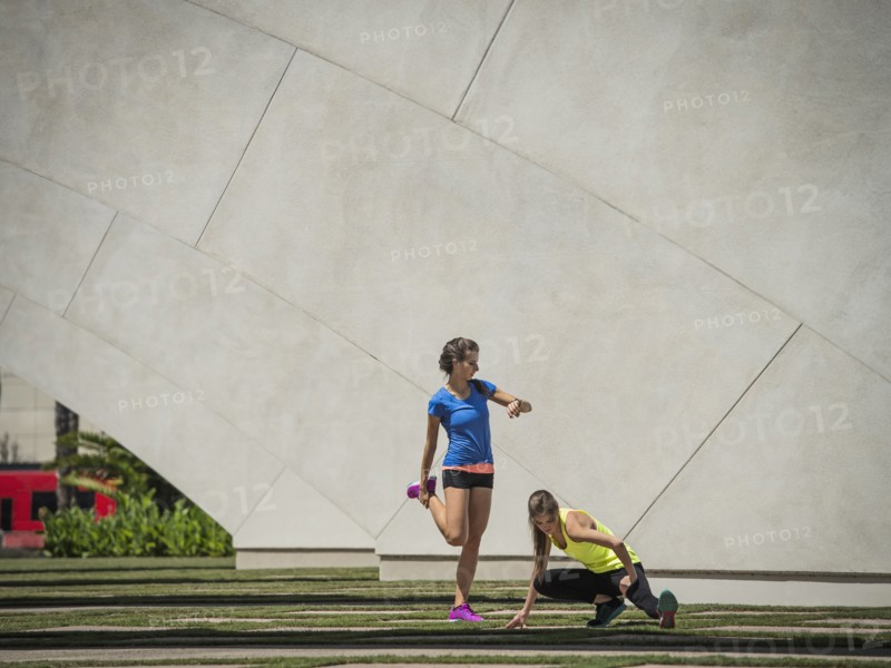 Caucasian women stretching legs near architecture
