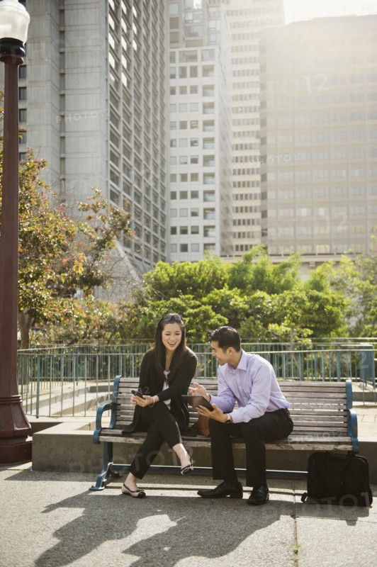 Chinese business people using technology on city bench