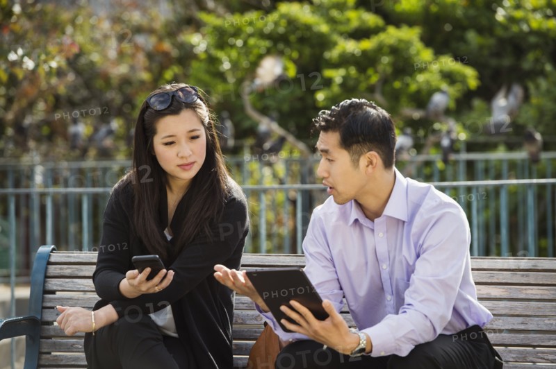 Chinese business people using technology on city bench
