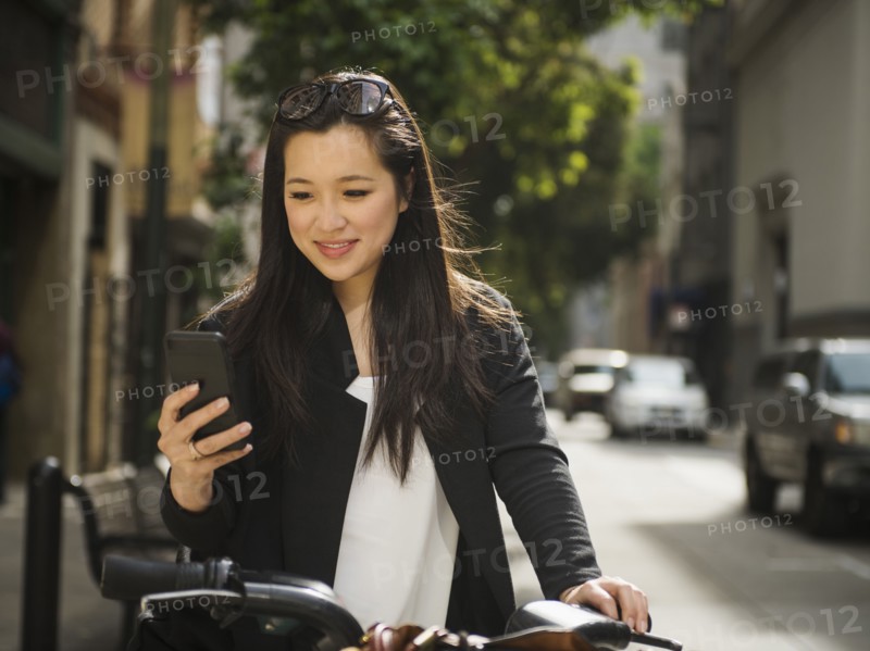 Chinese businesswoman on bicycle texting on cell phone