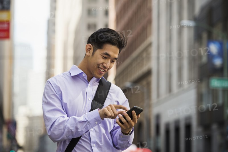 Chinese businessman texting on cell phone in city
