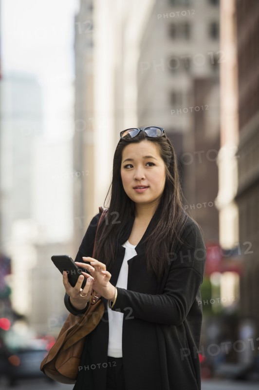Chinese businesswoman texting on cell phone in city