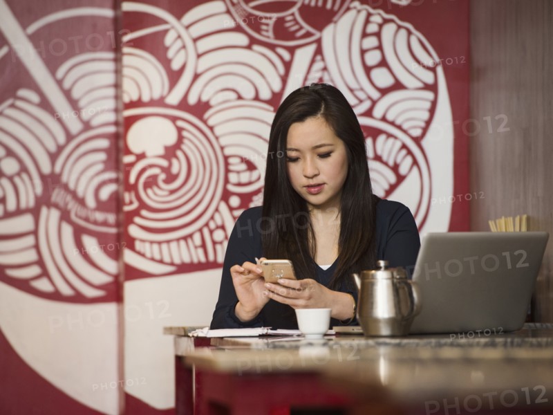 Chinese businesswoman texting on cell phone in restaurant