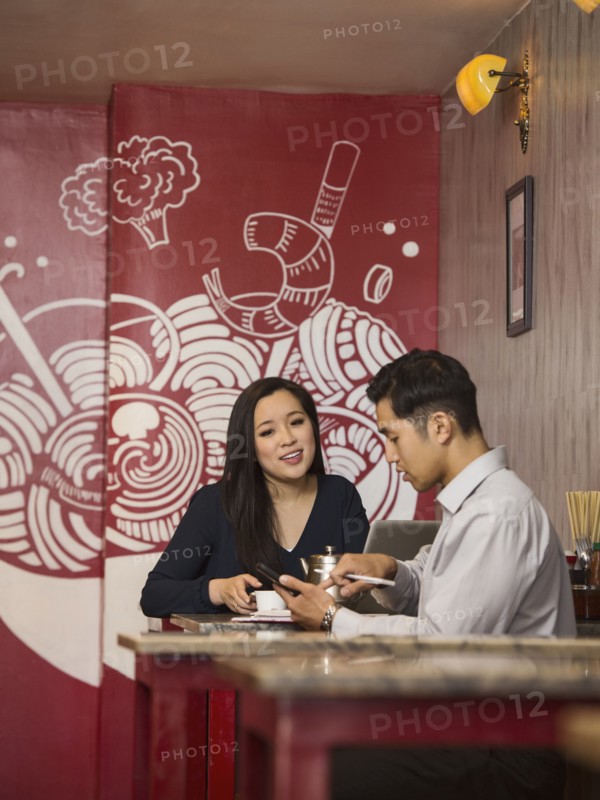 Chinese business people texting on cell phone in restaurant