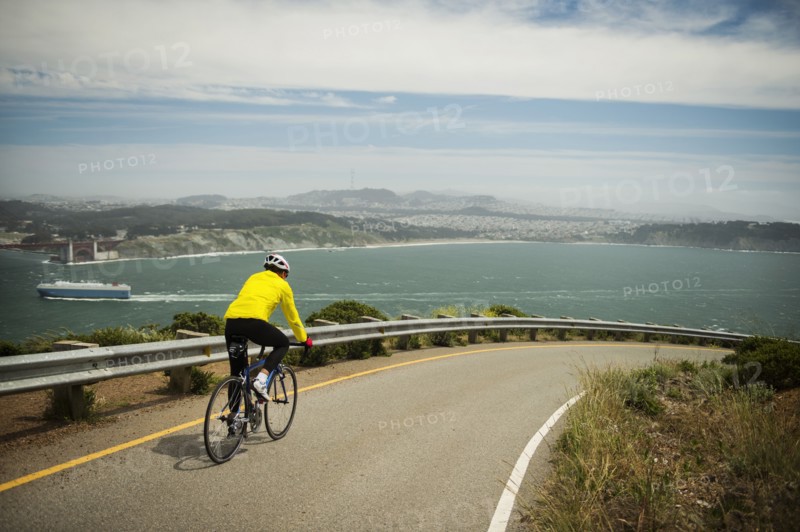 Hispanic man riding bicycle on waterfront road