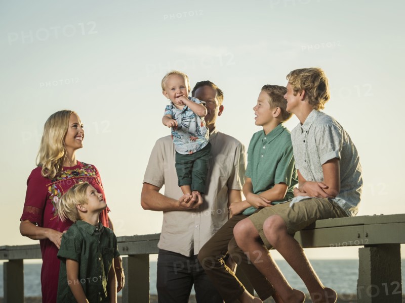 Caucasian family  watching baby boy stand on hands of father