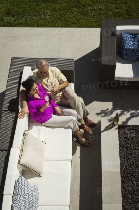 Older couple relaxing on modern backyard patio
