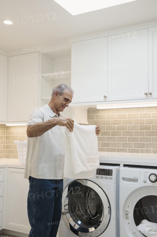 Caucasian man folding towel in modern laundry room