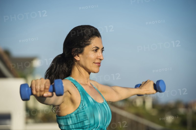 Hispanic woman lifting weights outdoors