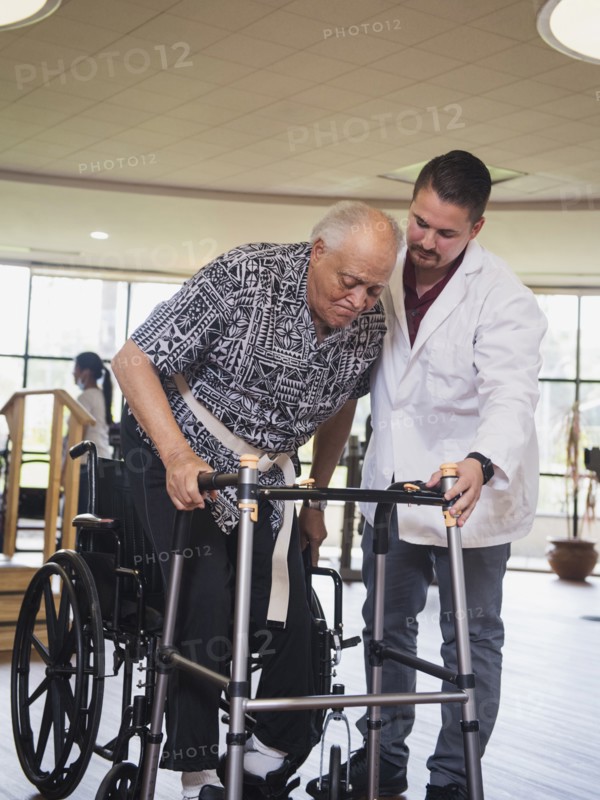 Physical therapist helping man in wheelchair use walker