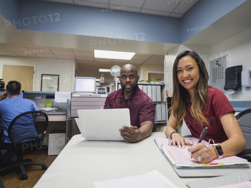 Portrait of smiling nurses with binders and hospital