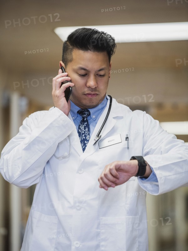 Filipino doctor talking on cell phone and checking the time