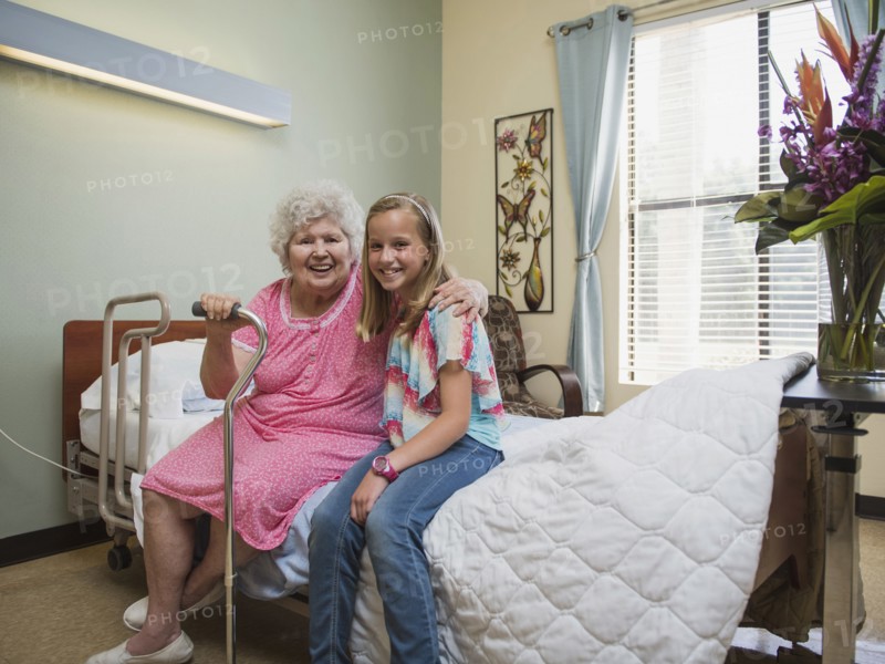 Smiling Caucasian woman sitting on bed with granddaughter