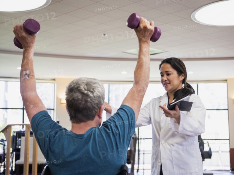 Physical therapist helping man lifting weights