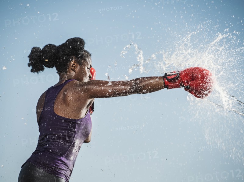 Water spraying on black woman boxing