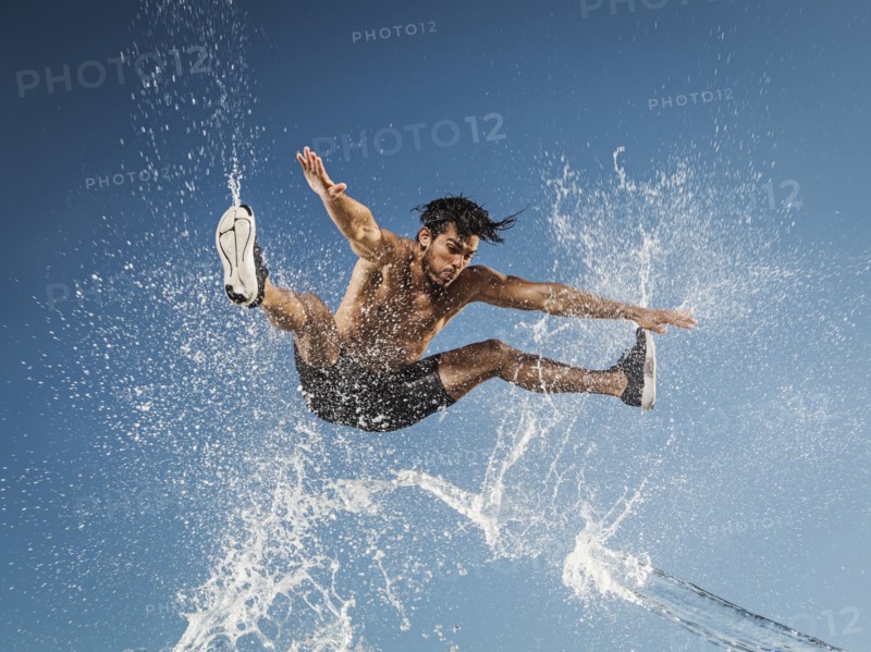 Water spraying on jumping Hispanic man
