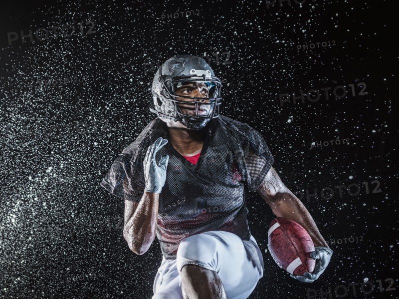 Water splashing on black football player running
