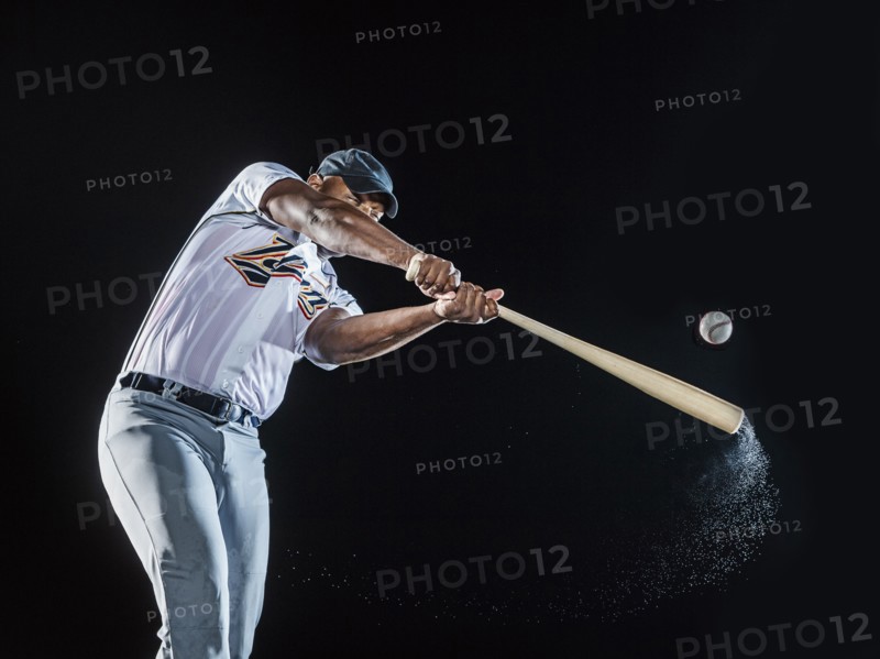 Water splashing from swinging bat of black baseball player