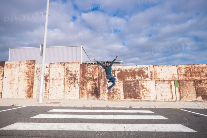 African American woman jumping for joy in crosswalk