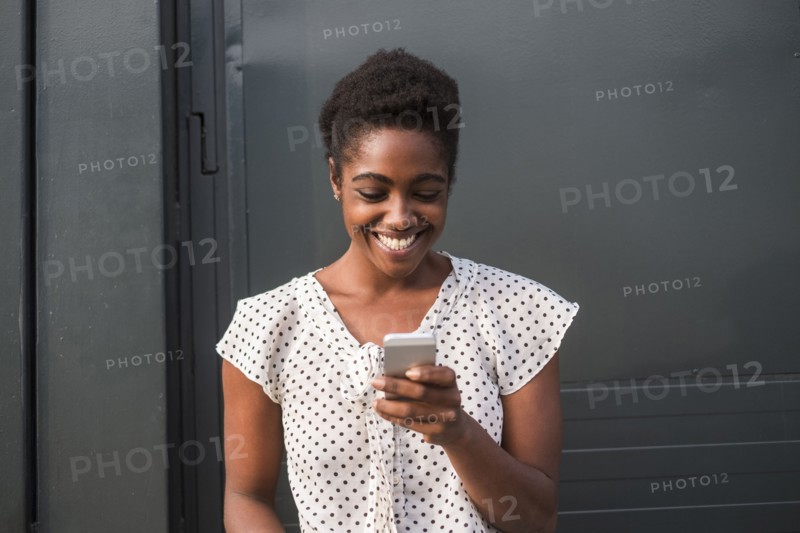 Smiling African American woman texting on cell phone
