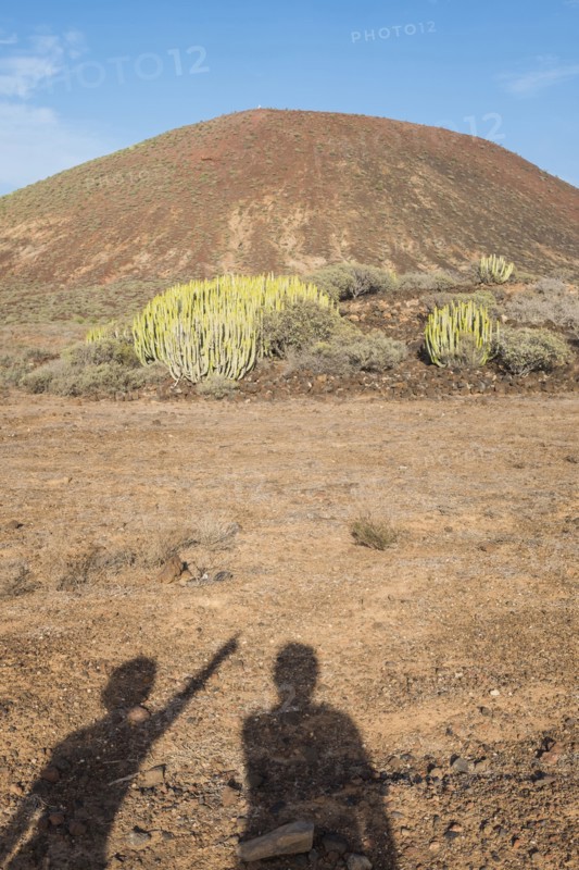 Shadows of people pointing at hill