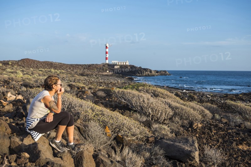 Caucasian woman sitting on rocks at ocean