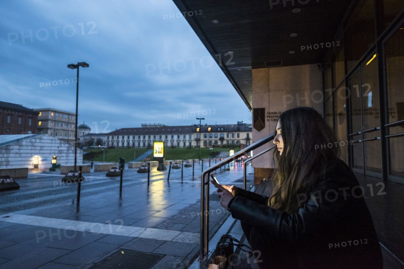 Caucasian woman sitting on staircase outdoors texting on cell phone