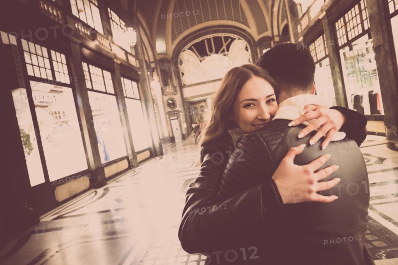 Smiling Caucasian couple hugging in lobby