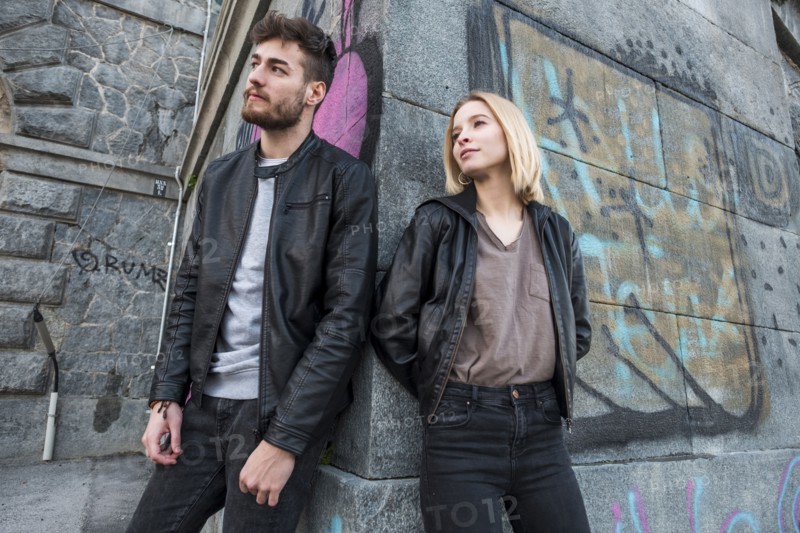 Caucasian couple leaning on wall with graffiti