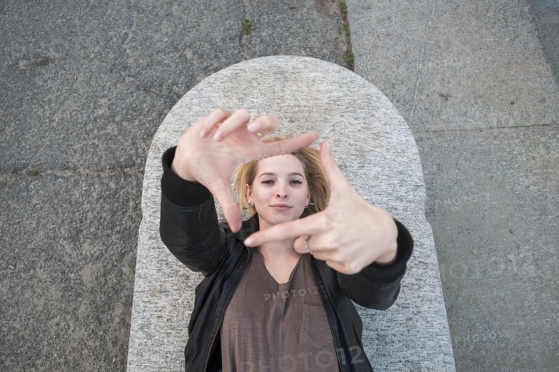 Caucasian woman laying on concrete gesturing square