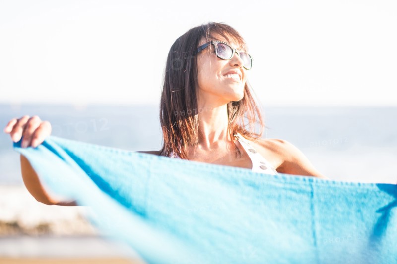 Caucasian woman holding blanket on beach