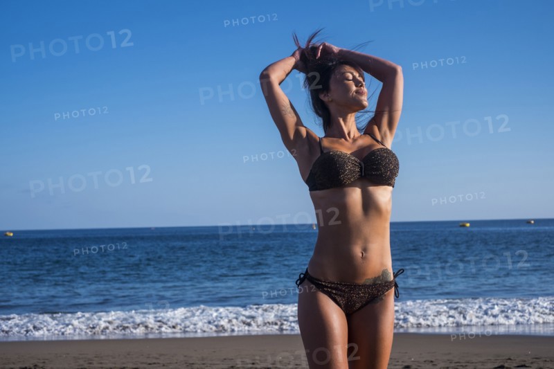 Caucasian woman standing on beach with hands in hair