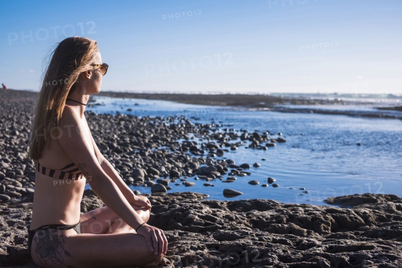 Caucasian woman sitting on beach wearing bikini