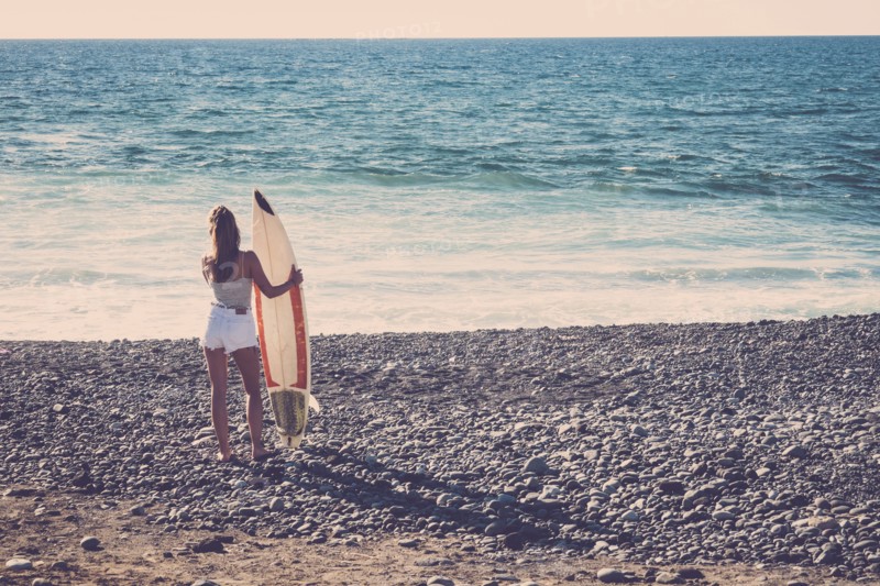 Caucasian woman standing on beach holding surfboard