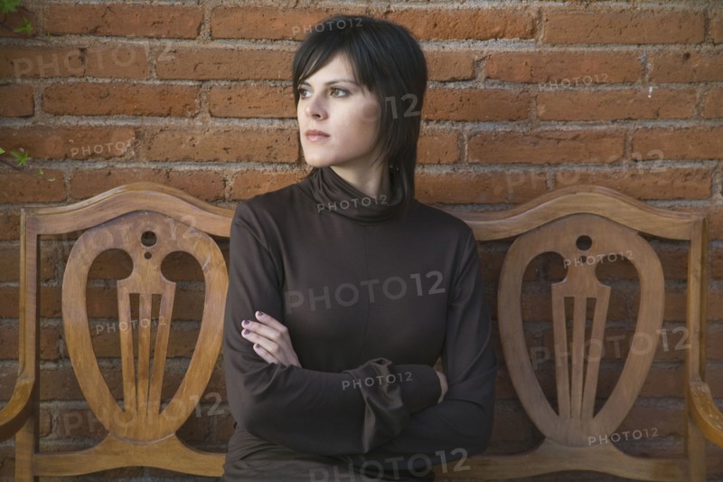 Frustrated Hispanic woman sitting on bench