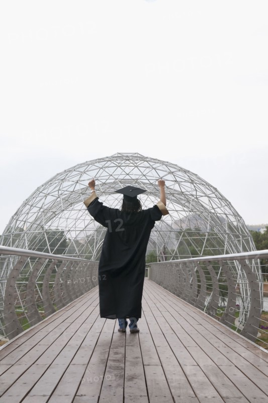 Mixed race graduate in cap and gown cheering