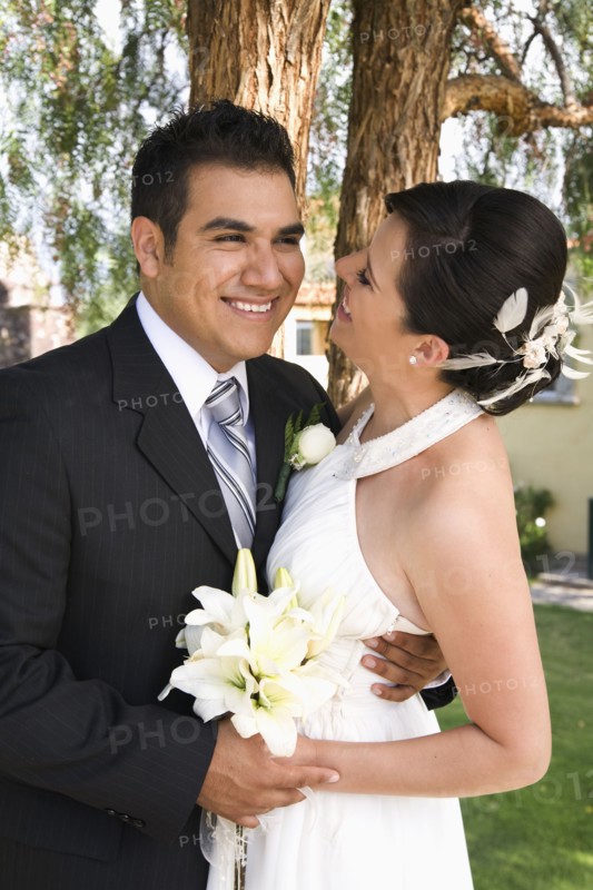 Hispanic bride and groom hugging