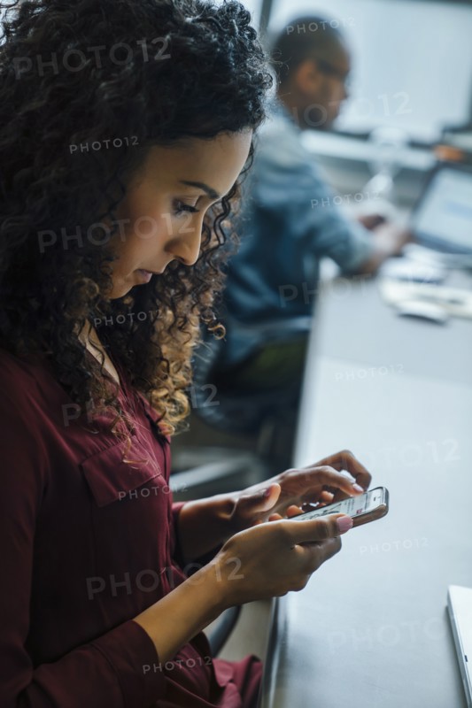 Businesswoman using cell phone in office