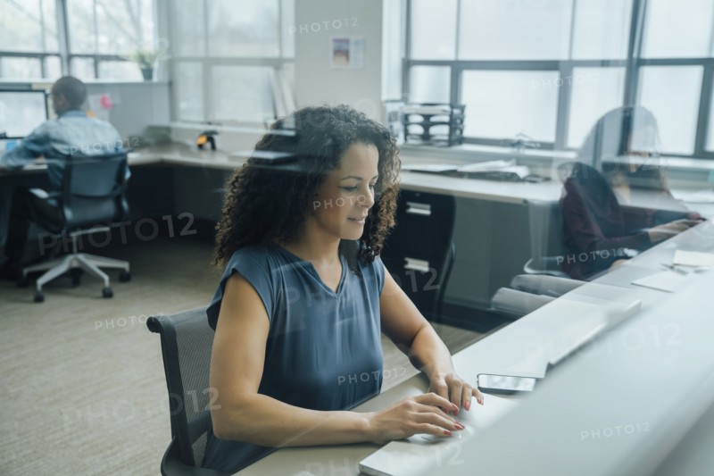 Businesswoman working in office behind window